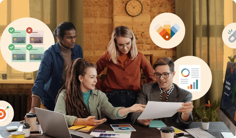 People sitting at a desk looking at computers and paperwork