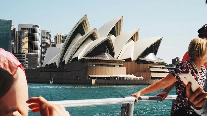 Image description: People’s hands on the edge of frame and out of focus while the opera house centered in clear view.