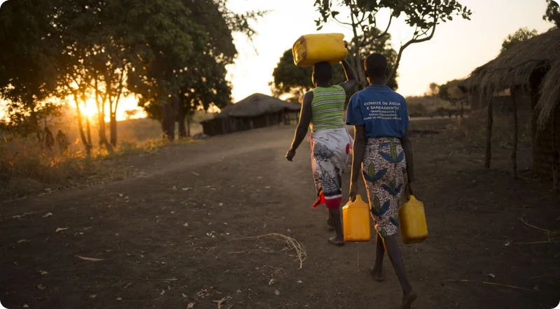 A photo of Natalia and another women carrying yellow jerry cans of water in Mozambique.