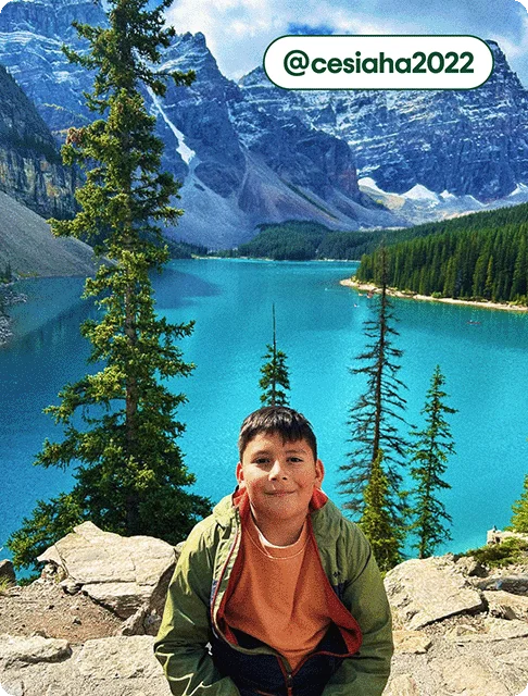 Image description: A young boy smiling in front of the turquoise waters of Moraine Lake, photo taken by @cesiaha2022