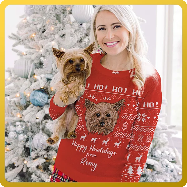 Girl stood in front of christmas tree holding her pup while wearing a red custom christmas pet face sweater