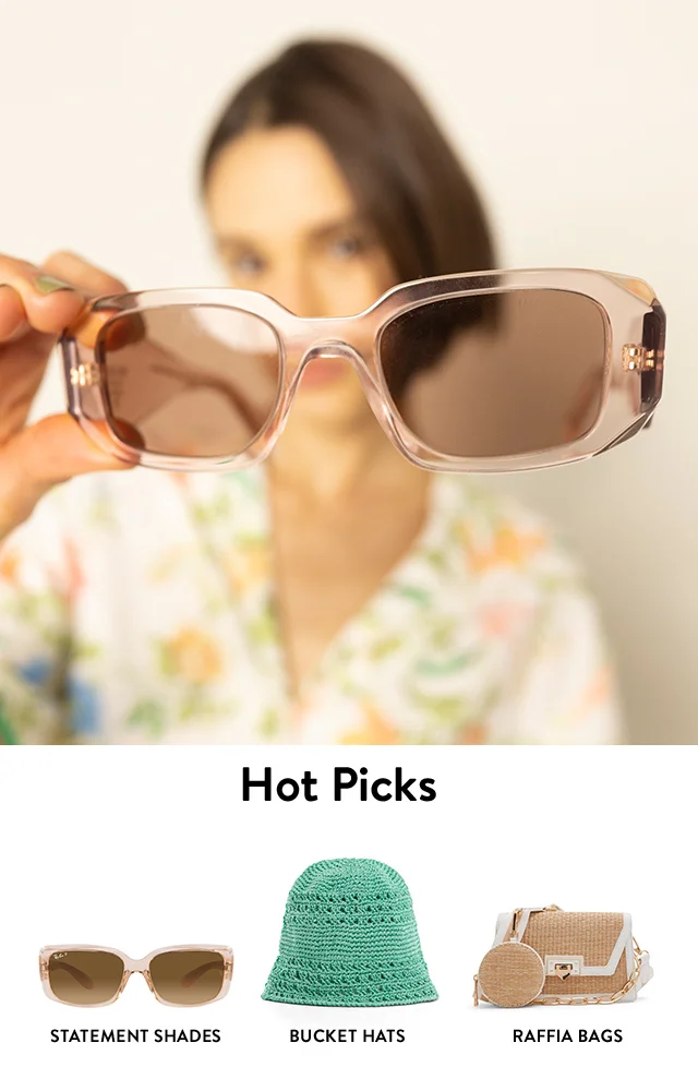 A woman holding clear rectangular sunglasses. Summer accessories: clear rectangular sunglasses, a bucket hat and raffia shoulder bag.