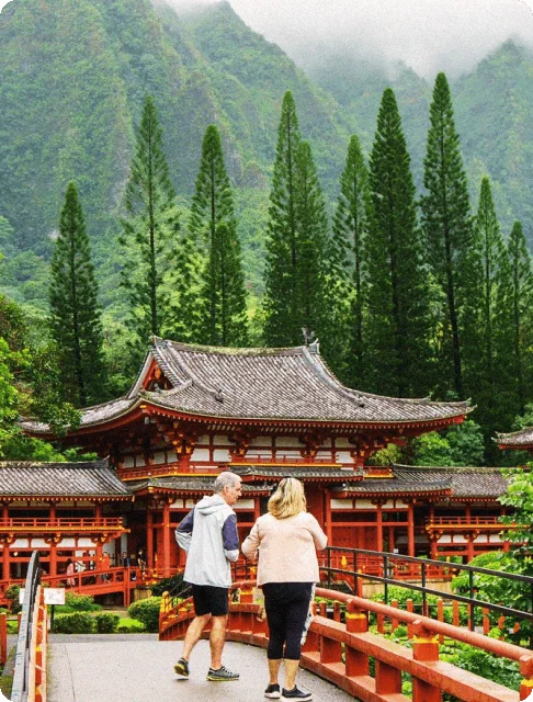 Image Description: A couple exploring Oahu’s famous Byodo-In Temple, with forested mountains in the background