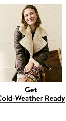 A woman wearing a brown coat with faux-shearling trim.