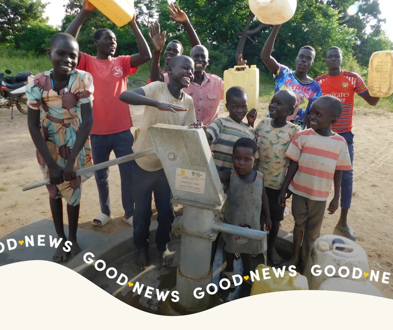 Young children stand around a hand pump.
