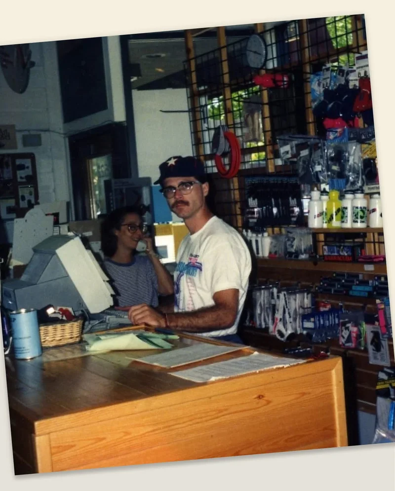 Two sales associates stand behind the counter of a running store.