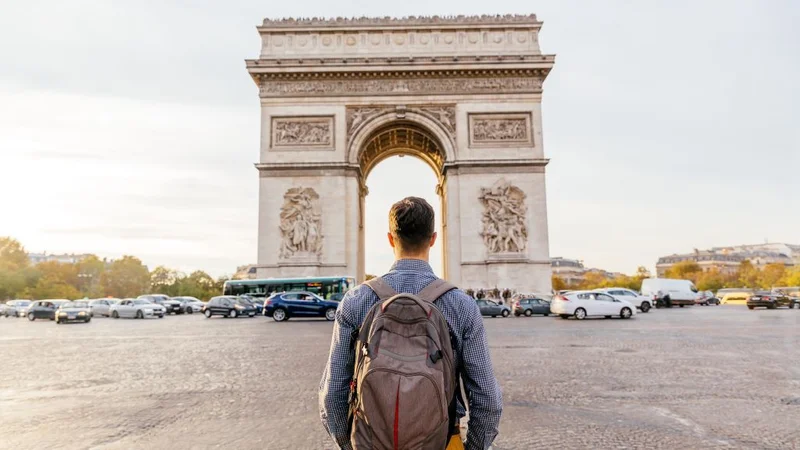 A traveler stands in front of the Arc de Triomphe in Paris, France
