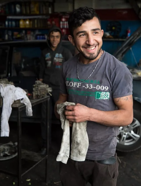 Image description: A man smiling in an auto mechanic shop.