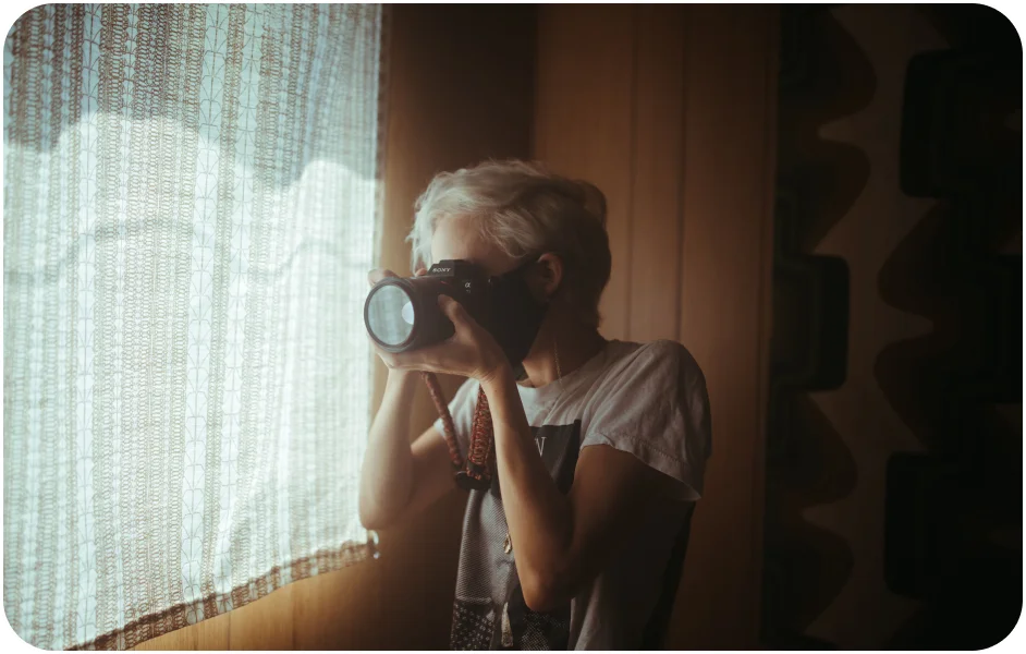 Image of a woman holding a camera illuminated by window light