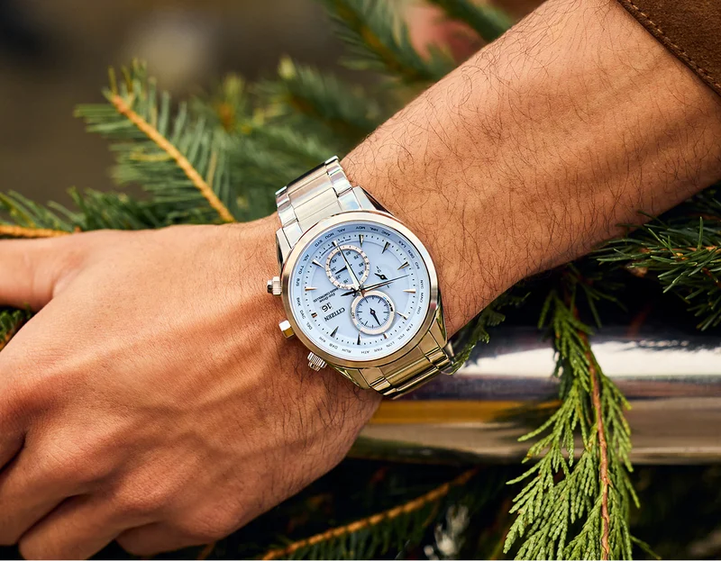 Stainless steel watch with a blue dial on a person's wrist.
