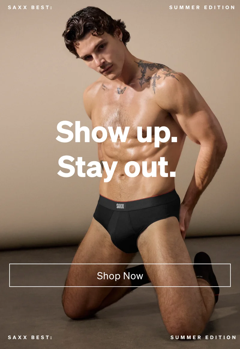 Model kneeling indoors wearing black SAXX briefs with “Show up. Stay out.” text and Shop Now CTA.