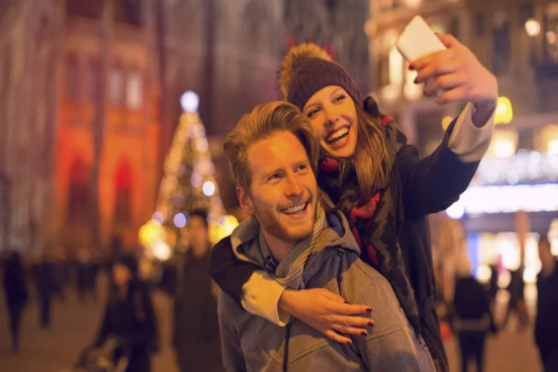 A couple take a photo against the backdrop of a Christmas market