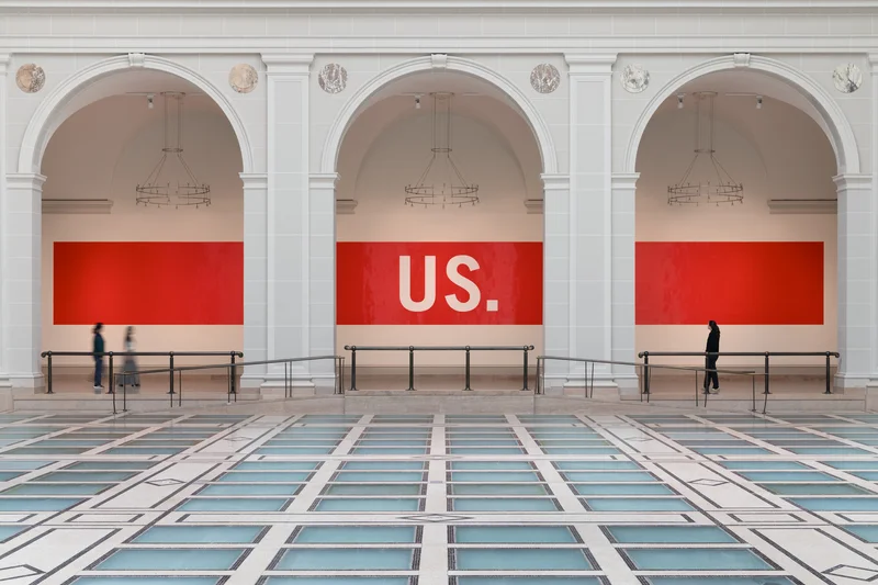 A photo of a red stripe on a white wall that reads "US."