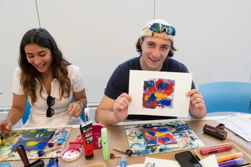 A man displaying his art print while a woman laughs beside him