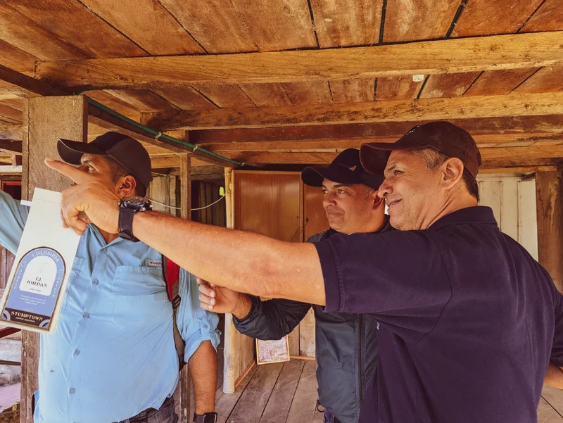 Reniel Perez and El Jordan coffee producers stand together inside a wooden structure.