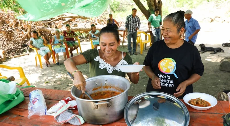 Image Description: Two people smiling while serving bowls of food.