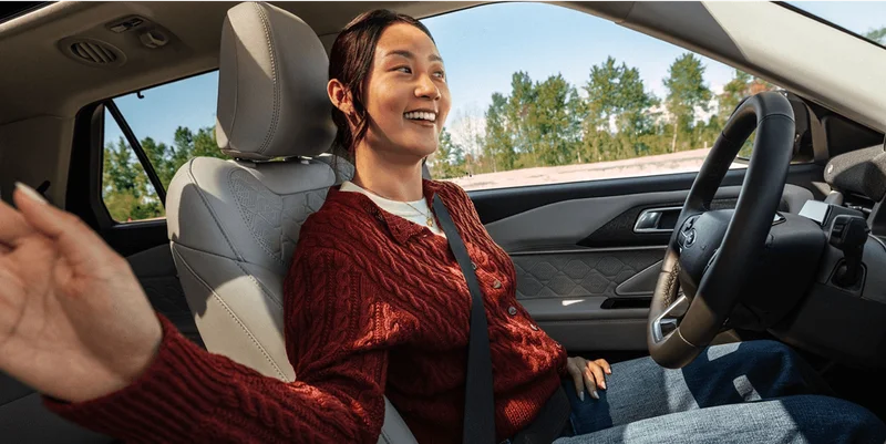 A smiling woman using BlueCruise hands‑free driving