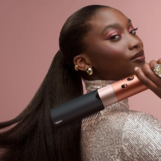 A model styles her hair with the Dyson Airwrap Co-anda2x multi-styler and dryer