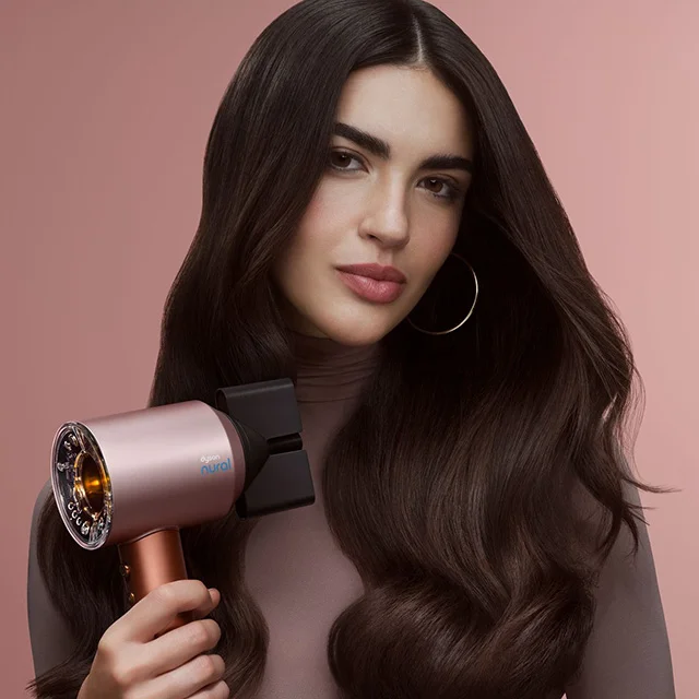 A model blow dries her hair with the Dyson Supersonic Nural hair dryer