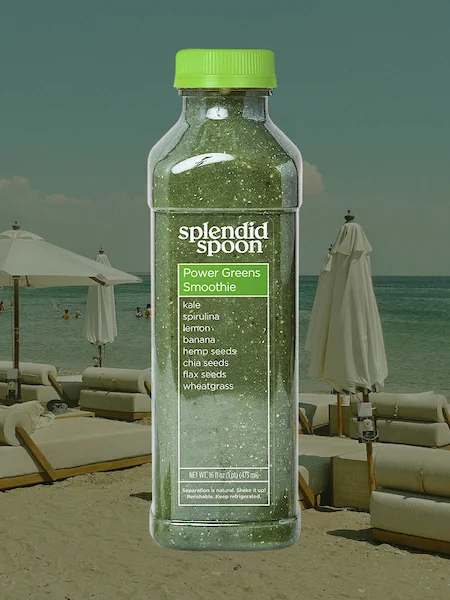 A power greens smoothie bottle with a beach scene behind.