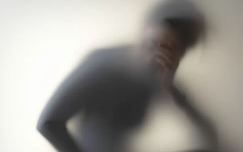 A woman holding her head obscured by a blur.