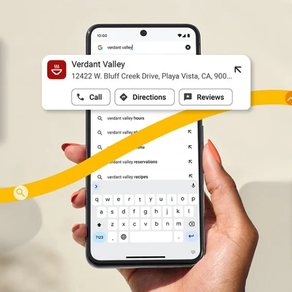 A hand with painted fingernails holds a cell phone, with the screen showing a restaurant listing with the option to call, find directions, or read a review.