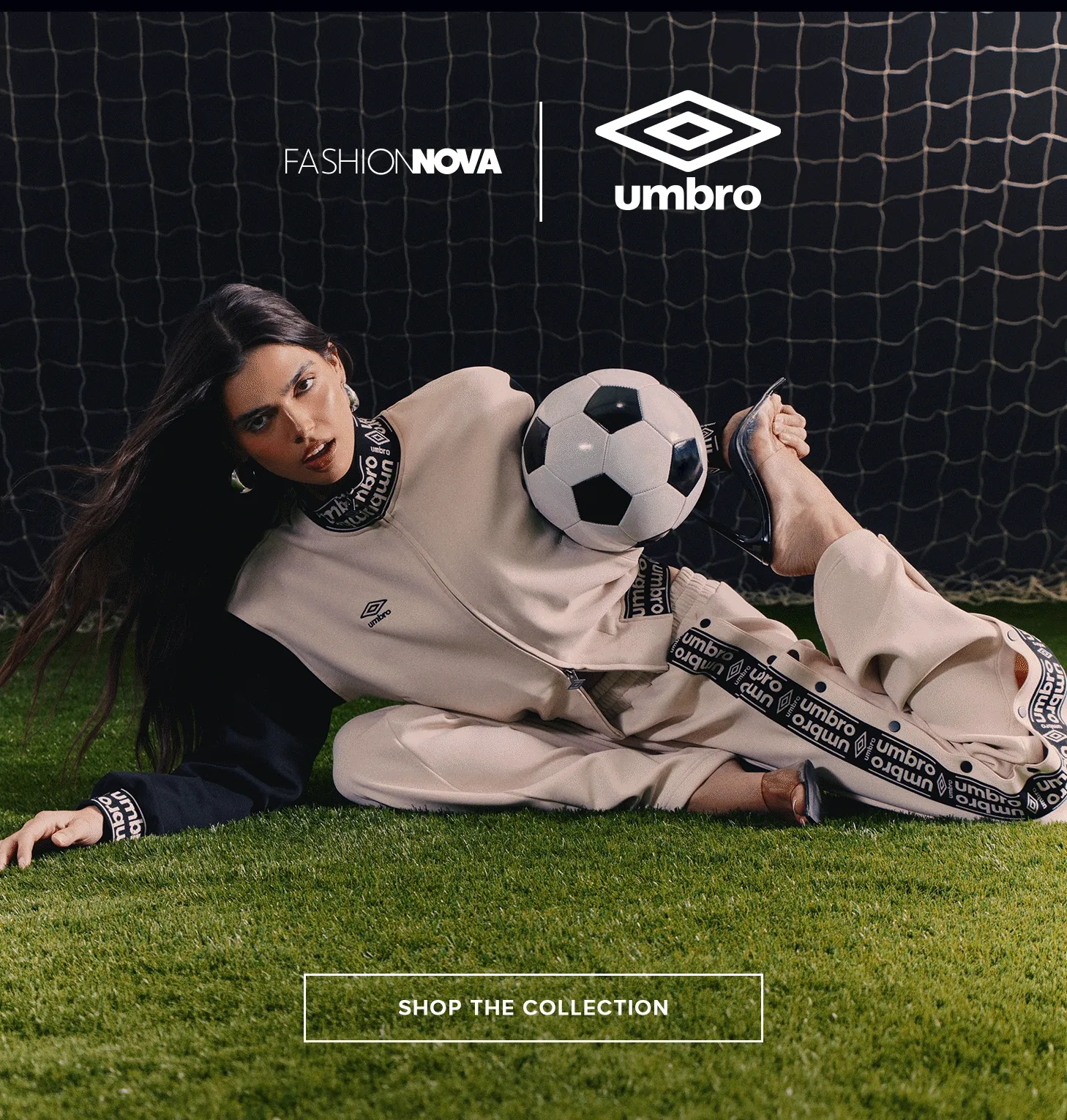 Fashion Nova & Umbro collaboration: Woman models beige athleisure tracksuit with soccer ball on grass. Shop the collection.