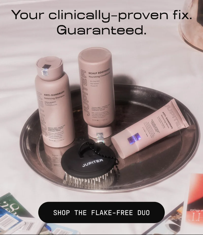 Jupiter Anti-Dandruff Balancing Shampoo, Scalp Soothing Nourishing Conditioner, Anti-Dandruff Restoring Serum, and Jupiter scalp brush displayed together on a metal tray. Headline reads "Your clinically-proven fix. Guaranteed." Button reads "Shop the Flake-Free Duo."