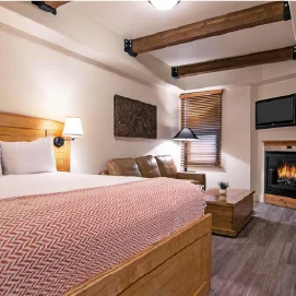 An aesthetically pleasing hotel room with a large bed, a leather couch, and
a fire going in the fireplace.