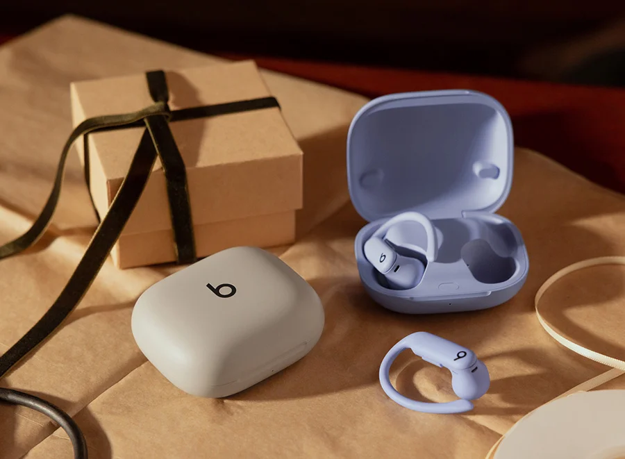 Powerbeats Pro 2 earbuds with charging case shown in gray and purple next to a wrapped gift.