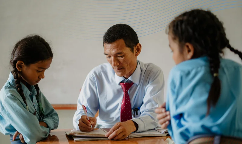 A photo of Netra teaching two young Nepalese girls