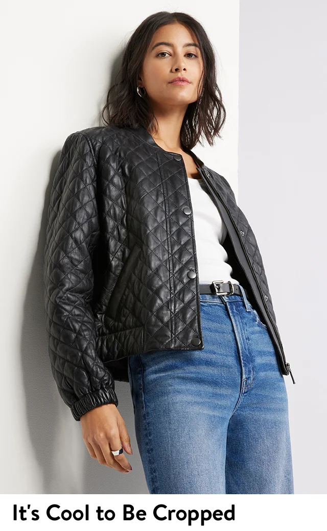 A woman wearing a black quilted leather jacket with a white top and blue jeans.