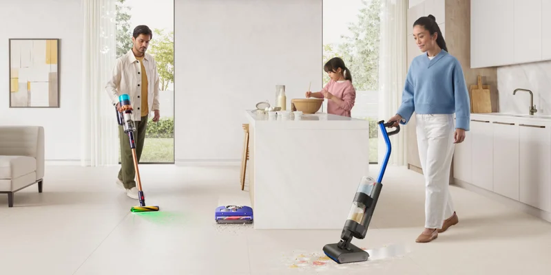 Young parents cleaning kitchen area with Dyson floorcare technology