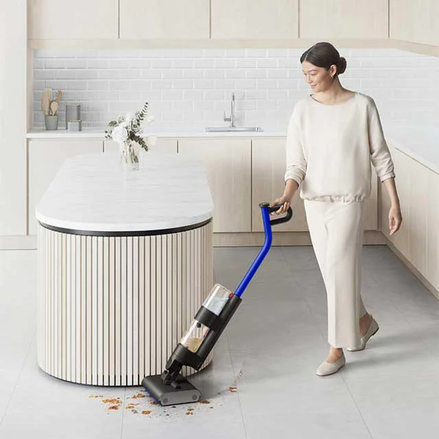 Woman cleans kitchen area with a Dyson WashG1 wet cleaner