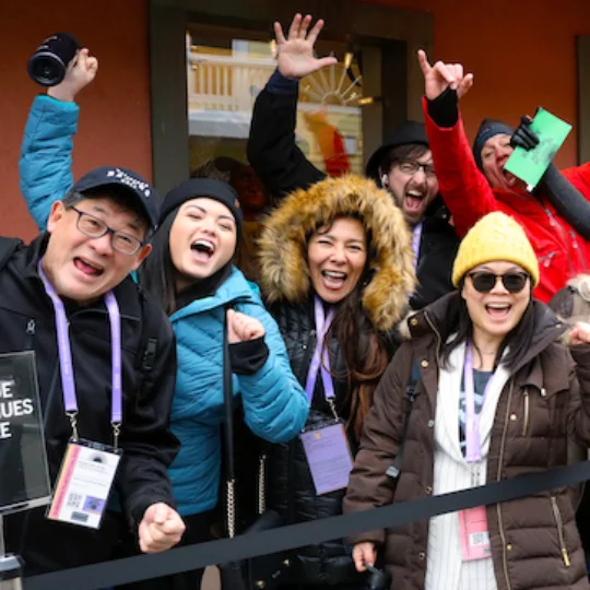 Six varied people cheering and looking happy to be in a Sundance Film
Festival queue.