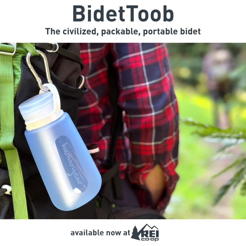 A person standing in a forest with a BidetToob, a small plastic container, hanging from his backpack