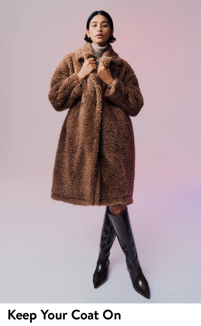 A woman wearing a brown teddy coat with knee-high boots.