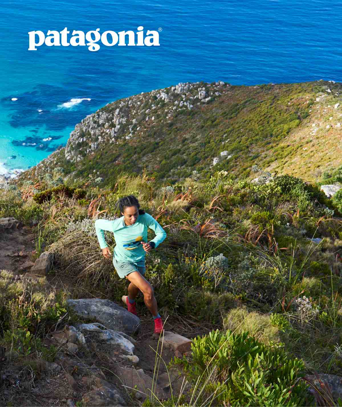 Patagonia. A person running up a steep trail on a cliff above the ocean.