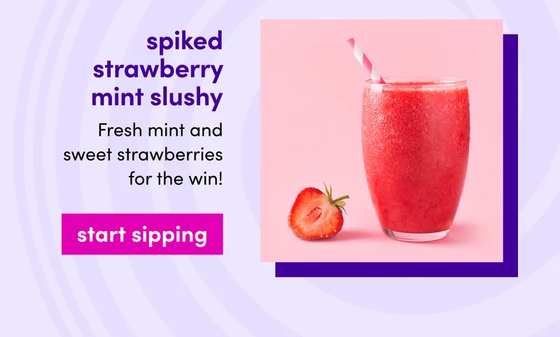 spiked strawberry mint slushy | Fresh mint and sweet strawberries for the win! | start sipping | Strawberry resting next to a glass of a frozen red drink with a pink striped straw.