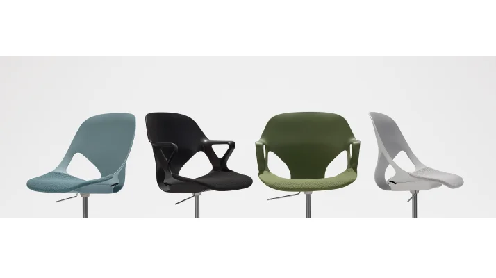 Four Zeph chairs in a row turned at different angles and focused on their seats. There is a light blue armless chair, black chair with fixed arms, olive chair with fixed arms and a light grey armless chair.