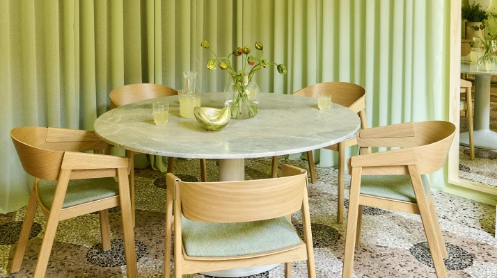 Green dining room with round dining table and oak side chairs.
