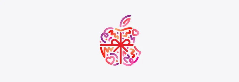 Dots, squiggles, and hearts in red, pink, and purple colors burst and spread across from behind Apple logo, wrapped in a red color bow, made up of dots, squiggles, and hearts in different hues of red, pink, and purple