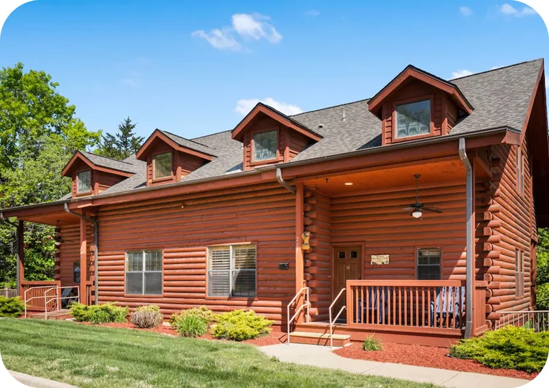 Log-style home with a covered front porch, dormer windows, and landscaped yard.