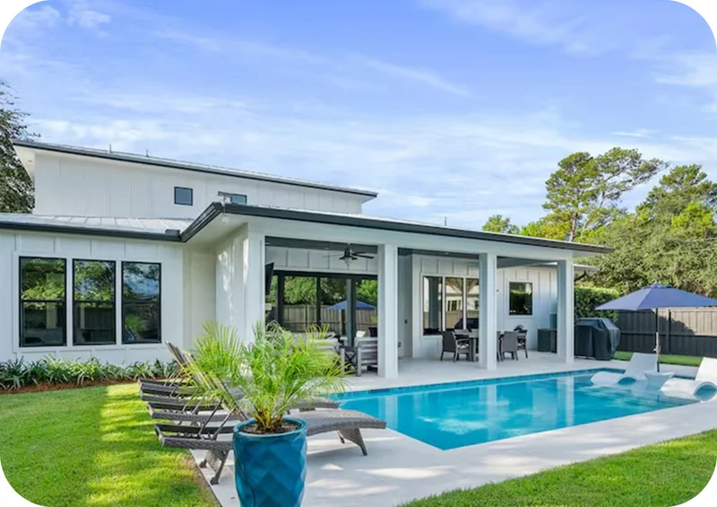Modern home with large windows opening to a backyard pool and outdoor seating area.