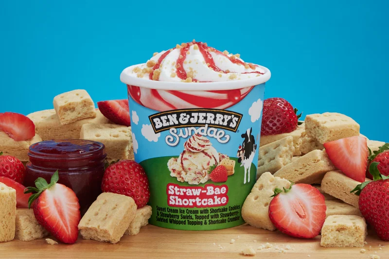 Pint of Ben & Jerry's Straw-Bae Shortcake Sundae ice cream with strawberries and shortcake pieces around it.