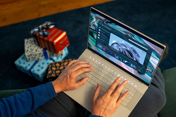A person next to gift-wrapped boxes using their Dell laptop computer to generate greeting card text.