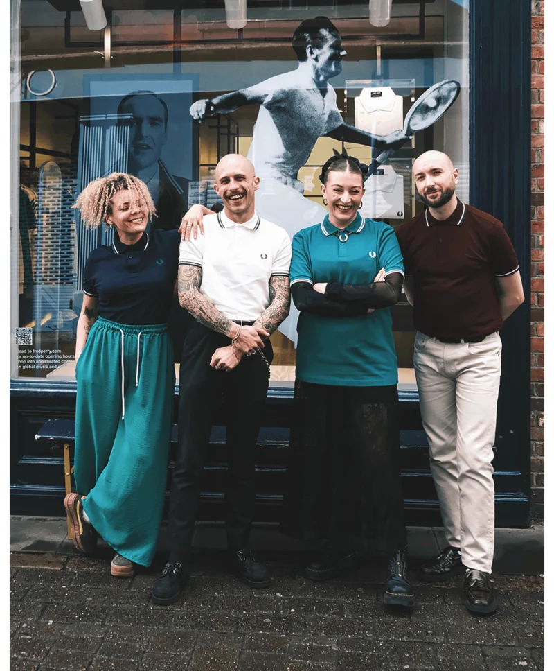 4 Fred Perry retail workers (2 men, 2 women) smiling and standing outside the Fred Perry Nottingham store