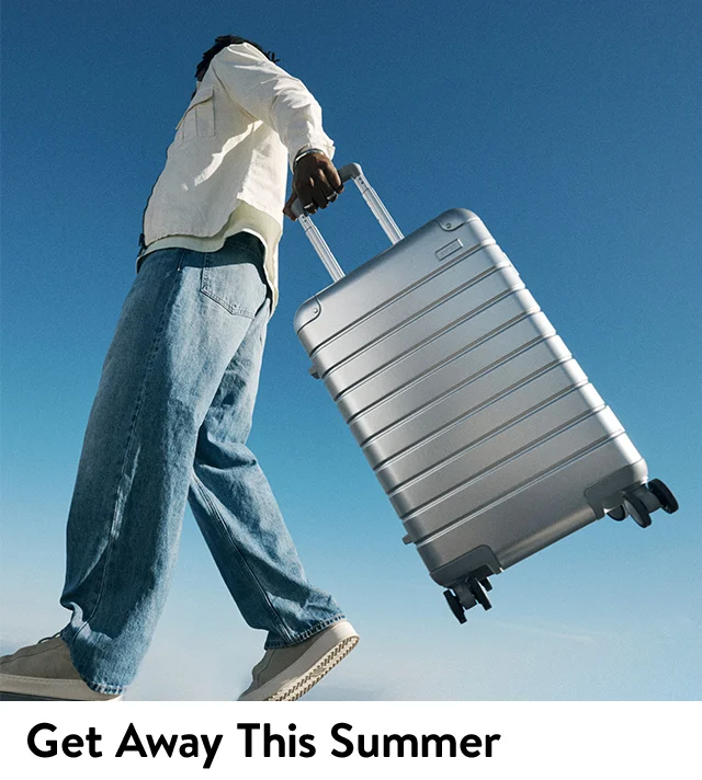A traveler carrying a silver roller suitcase.