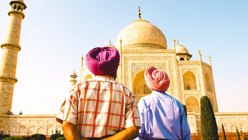 Image description: Two men viewing the exterior of the Taj Mahal.