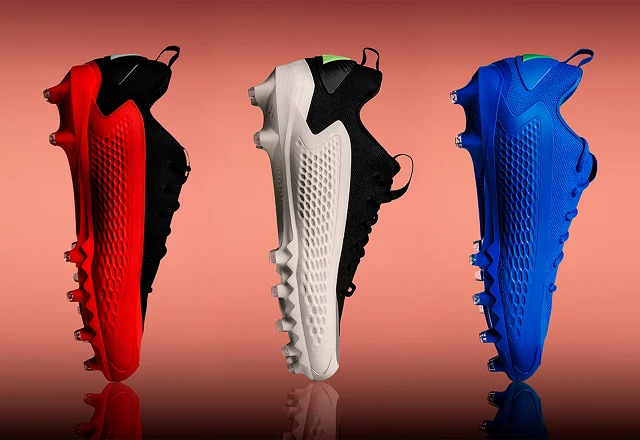 Three Anthony Edwards 1 Cleats in rec, white and blue stand vertically over a peach backdrop